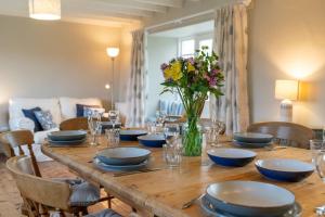 a wooden table with blue dishes and a vase of flowers at Penrose Cottage in Bude