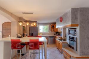 eine Küche mit einer Insel mit roten Barhockern in der Unterkunft Chez Céline - Superbe Villa climatisée avec 4 chambres indépendantes et piscine privée in Le Grau-du-Roi
