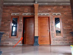2 portes en bois sur un bâtiment en briques avec une flèche orange dans l'établissement Wisma Sadewa, à Pangenjurutengah