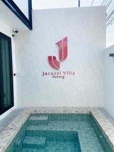 ラノーンにあるJ Jacuzzi Villa Ranongの建物の横に看板のあるスイミングプール