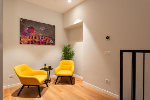 duas cadeiras amarelas num quarto com uma pintura na parede em Major House - Luxury Apartments em Roma