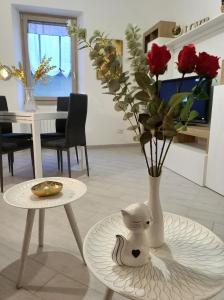 a white vase sitting on a table next to a table with roses at Gregorihouseroma in Rome