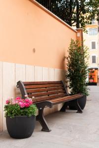 una panca di legno seduta accanto a un muro con fiori di Major House - Luxury Apartments a Roma