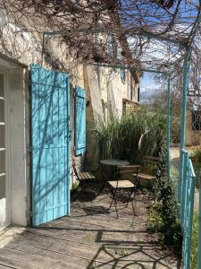 Une porte ouverte s'ouvre sur une terrasse avec une table et des chaises. dans l'établissement Authentique Mazet et sa fontaine en Provence, à Fontvieille