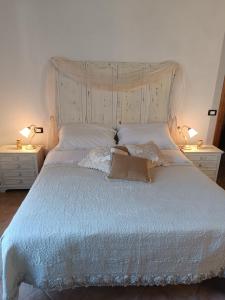 a white bed with two lamps on two tables at Shabby House in Podere Modello