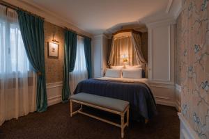 ein Schlafzimmer mit einem Bett mit einer blauen Decke und Vorhängen in der Unterkunft Hôtel De Buci in Paris