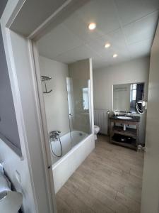 a bathroom with a tub and a toilet and a sink at Hotel Heritage in De Haan +21 photos