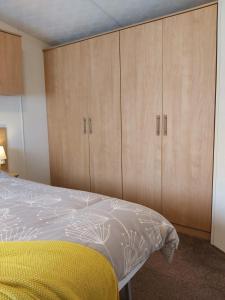 a bedroom with a bed and wooden cabinets at Endless Summer in Barnstaple