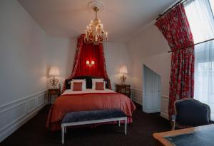 a bedroom with a red bed with a chandelier at Hôtel De Buci in Paris