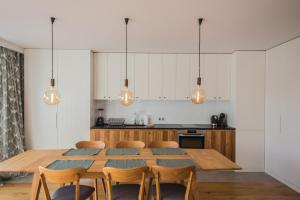 uma cozinha com uma mesa de madeira e cadeiras em Apartview Bukowa II by Rent like home em Wisla
