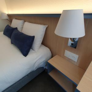 1 dormitorio con 1 cama con lámpara. en Kyriad Villefranche Sur Saone, en Villefranche-sur-Saône