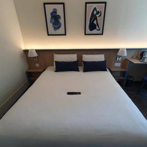 ヴィルフランシュ・シュル・ソーヌにあるキリアド ヴィルフランシュ シュル ソーヌのテーブル2台付きの客室で、白い大型ベッド1台が備わります。
