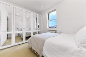 ein weißes Schlafzimmer mit einem großen Bett und einem Fenster in der Unterkunft Royal Kensington 1 Bedroom Apartment in London