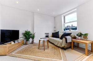 ein Wohnzimmer mit einem Sofa und einem TV in der Unterkunft Royal Kensington 1 Bedroom Apartment in London