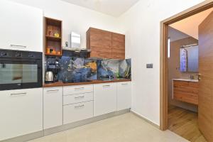 une cuisine avec des armoires blanches et un appareil noir dans l'établissement Apartments Vili 351, à Fažana
