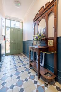 a hallway with a green door and a table with a mirror at Boutique Stays at 78 in Bangor