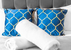 twee blauwe en gouden kussens op een bed bij New 2 Bedroom Deluxe Apartment - Parking - Wifi & Netflix - Top Rated - 50C in Sleightholme