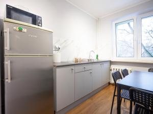 a kitchen with a refrigerator and a table with chairs at WAW Pokoje Ursynów in Warsaw