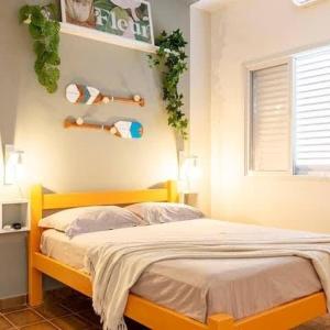 a bedroom with a yellow bed and a window at Casa Aconchego - O refúgio perfeito para amar e descansar in Peruíbe