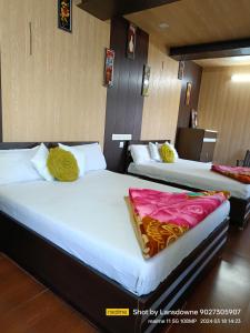 two beds in a hotel room with yellow and pink sheets at Joshi Holiday Home Stay in Lansdowne