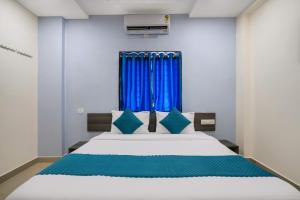 a bedroom with a large bed with blue curtains at The Balcony Suites in Hyderabad +69 photos