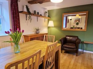 a dining room with a wooden table and a chair at Barnyard Cottage in Leighton Buzzard