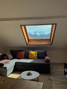 ein Wohnzimmer mit einem Sofa und einem Fenster in der Unterkunft Cocon sous les toits in Albertville