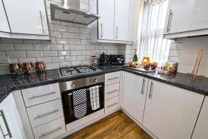 een keuken met witte kasten en een fornuis met oven bij Heathrow RARE find 2 Bedroom plus 2 Bathroom flat - Sleeps 6- Free Parking- Close to Heathrow Terminals-Quiet development in Stanwell