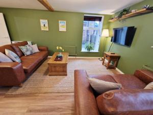 a living room with leather couches and a television at The Mill in Leighton Buzzard