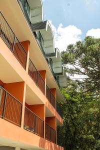 an orange apartment building with balconies and trees at Pousada Hogareña in Campos do Jordão
