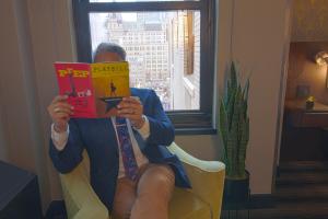 a woman sitting in a chair reading a book at Hotel Edison Times Square in New York