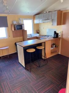 a kitchen with a counter and stools in it at Mobil Home 5 personnes - Camping *** Les Ollivaud- in La Baule