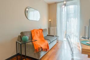 sala de estar con sofá y manta naranja en Loft Sterlizia, by R Collection Apartment, en Milán