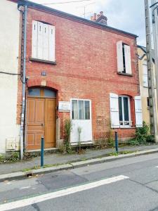 um edifício de tijolos vermelhos com uma porta castanha numa rua em Charmant et paisible duplex à gare Rennes em Rennes