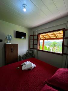 a bedroom with a red bed and a window at Pousada Vista Pedra Azul in Pedra Azul