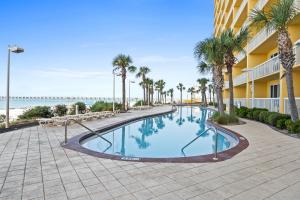 a swimming pool at the beach with palm trees and a building at Calypso Beach Resort in Panama City Beach