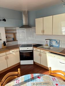 a kitchen with white cabinets and a stove top oven at L'Imprenable vue mer in Crozon