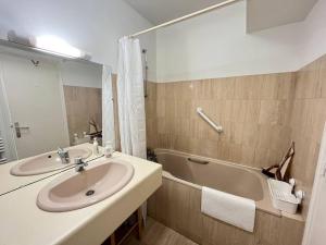 een badkamer met een wastafel en een bad bij Le Sextant Conciergerie Yourhosthelper in Larmor-Plage