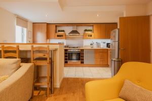 a kitchen with wooden cabinets and a yellow couch at Charming city centre 2 bed apartment - Sleeps 4. With Parking. in Chester