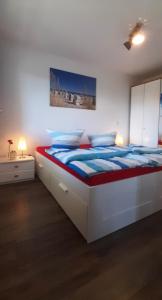 a white bedroom with a large bed with blue sheets at Ferienwohnung Wellenreiter 200 m zum Strand Fewo strandnah mit Balkon Parkplatz Wlan in Karlshagen