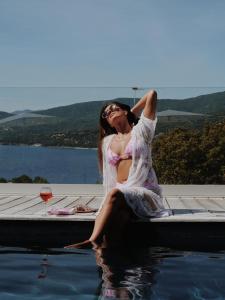 une femme assise dans l'eau à côté d'une piscine dans l'établissement Résidence & Hôtel Aria Marina, à Propriano