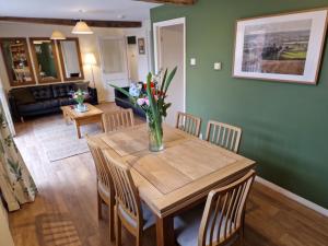 a dining room table with a vase of flowers on it at Cowman's Cottage in Leighton Buzzard