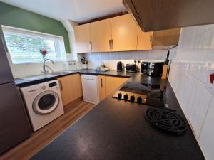 a kitchen with a stove and a washer and dryer at Cowman's Cottage in Leighton Buzzard +11 photos