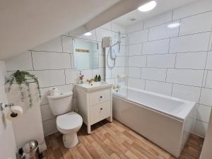 a bathroom with a toilet and a tub and a sink at Cowman's Cottage in Leighton Buzzard