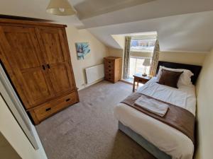 a bedroom with a large bed and a wooden cabinet at Cowman's Cottage in Leighton Buzzard