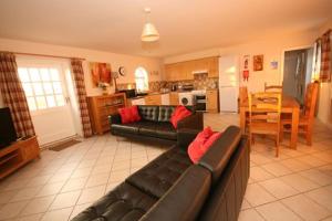 a living room with a couch and a kitchen at Grooms Cottage in Leighton Buzzard