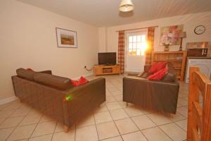 a living room with two couches and a kitchen at Grooms Cottage in Leighton Buzzard