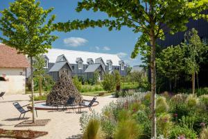 a garden with chairs and a building in the background at Le Bois des Chambres in Chaumont-sur-Loire