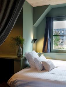 - un lit avec des oreillers blancs dans une chambre avec une fenêtre dans l'établissement Le Bois des Chambres, à Chaumont-sur-Loire