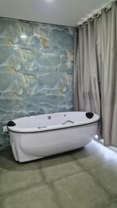 a bath tub in a bathroom with a stone wall at Pousada Recanto Família Suíte com Hidro in Paraty